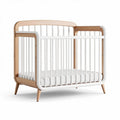 Wooden toddler crib with removable mattress and safety rail in natural finish